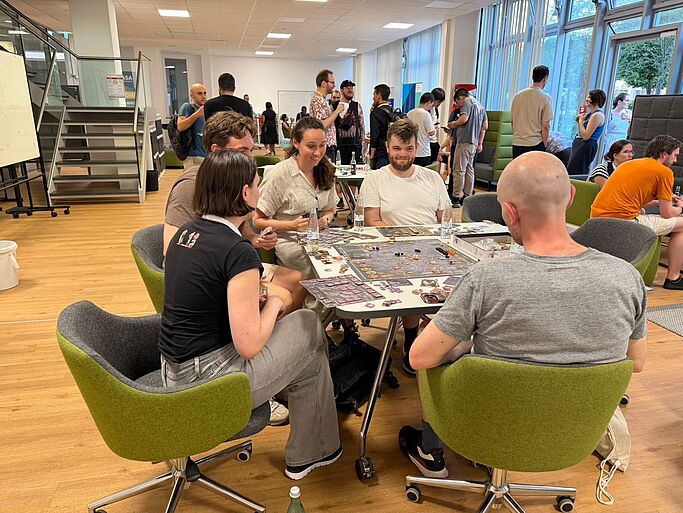 Several people sitting at tables in a bright room talking