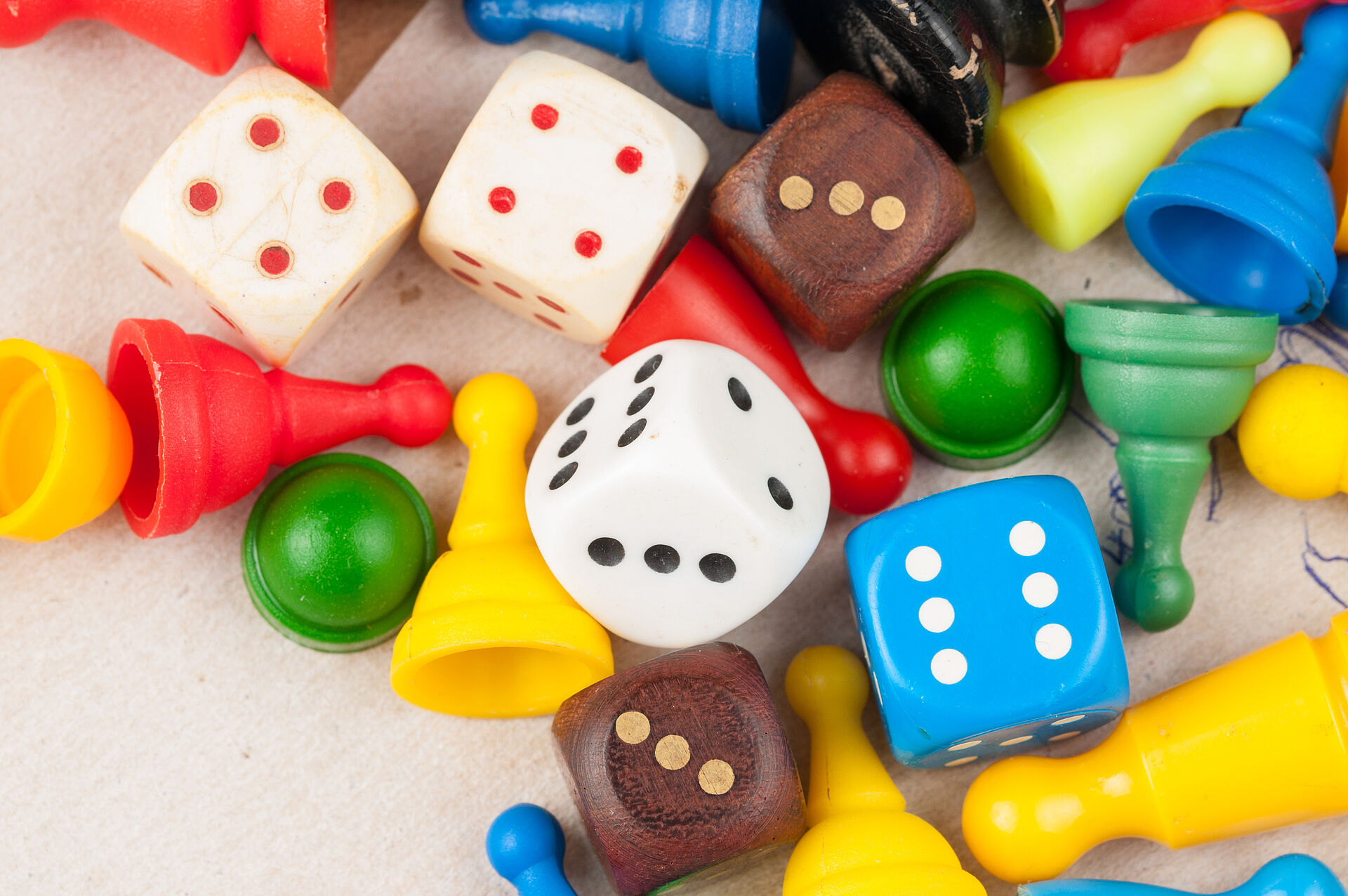 Several colorful game pieces and dice made of wood and plastic scattered on a light surface